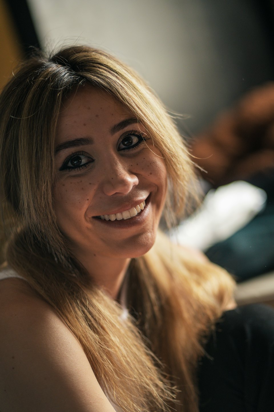 Blonde woman with freckles smiling in an indoor space.