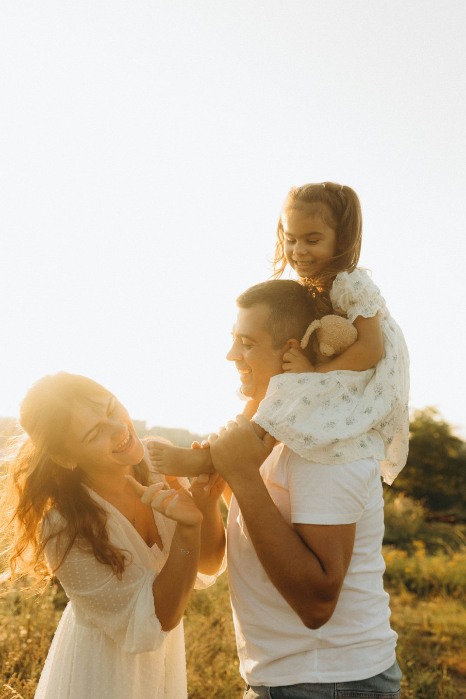 Family laughing together while walking through a field of grass.